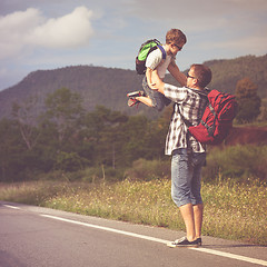 Image showing Father and son walking on the road at the day time.