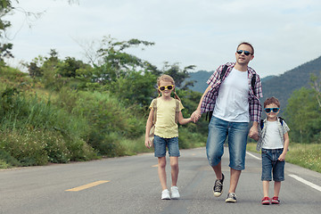 Image showing Father and children walking on the road at the day time. 