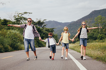 Image showing Father and children walking on the road at the day time.