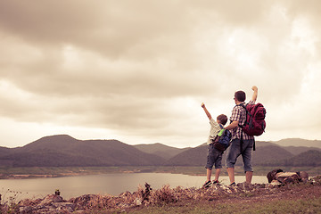 Image showing Father and son standing near the lake at the day time.