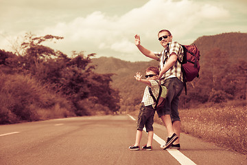 Image showing Father and son walking on the road at the day time. 