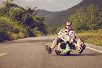 Image showing Father and son playing  on the road at the day time.