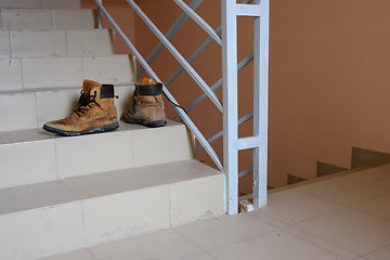 Image showing On the steps of the stairs are old shoes