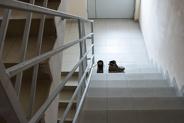 Image showing Abandoned shoes stand on the stairs in the entrance