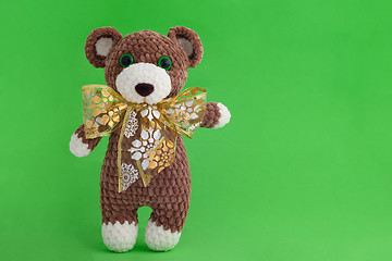 Image showing Children\'s knitted toy bear with bow on a green background
