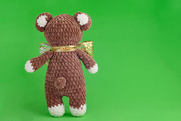 Image showing Children\'s knitted toy bear with bow on a green background