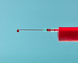 Image showing Close-up needle of plastic syringe with drop of red liquid.