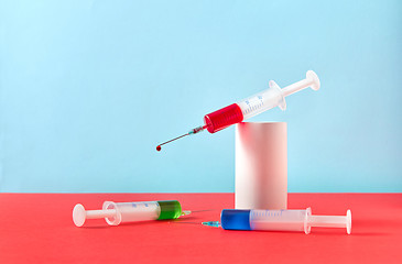 Image showing Two syringes with vaccine and one with red drop on a plaster cylinder.