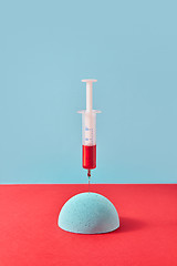 Image showing Injection of syringe with red liquid into styrofoam hemisphere.