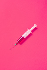 Image showing Disposable syringes of hot pink vaccine with soft shadows.