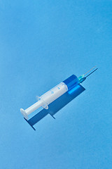 Image showing Disposable syringe of blue liquid or vaccine with shadow.