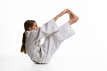 Image showing A girl in a sports kekogi reaches her hands at her feet, waving a stretch