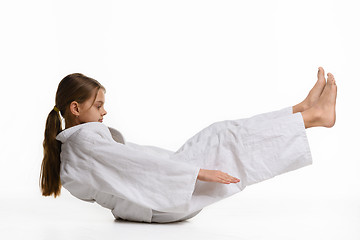 Image showing Girl judoka performs warm-up and reaches her hands to her feet