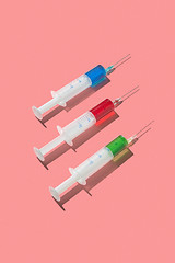 Image showing Multicolored serum in three plastic disposable syrenges.