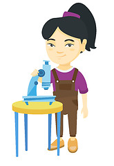 Image showing Little asian schoolgirl using a microscope.