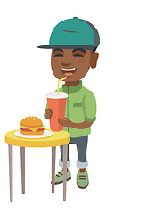 Image showing Little boy drinking soda and eating cheeseburger.