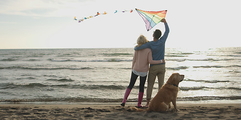 Image showing couple with dog having fun on beach on autmun day