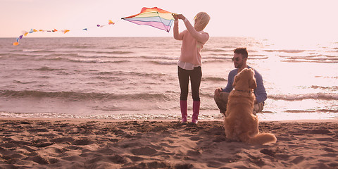 Image showing couple with dog having fun on beach on autmun day