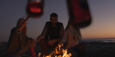 Image showing Young Friends Making A Toast With Beer Around Campfire at beach