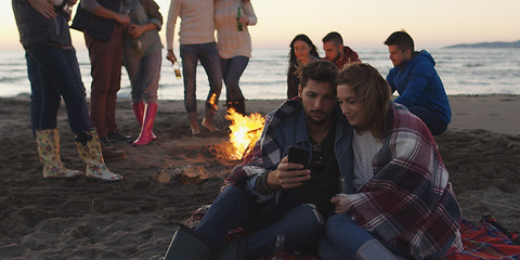 Image showing Couple enjoying bonfire with friends on beach