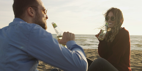 Image showing Loving Young Couple Sitting On The Beach beside Campfire drinkin
