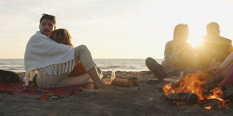 Image showing Loving Young Couple Sitting On The Beach beside Campfire drinkin