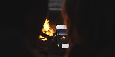 Image showing Couple taking photos beside campfire on beach