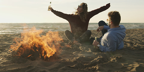 Image showing Loving Young Couple Sitting On The Beach beside Campfire drinkin