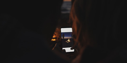 Image showing Couple taking photos beside campfire on beach