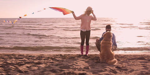 Image showing couple with dog having fun on beach on autmun day