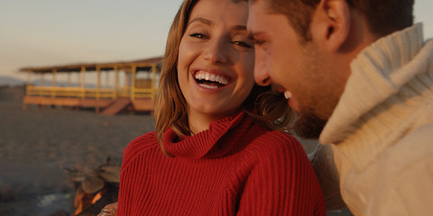 Image showing Loving Young Couple Sitting On The Beach beside Campfire drinkin