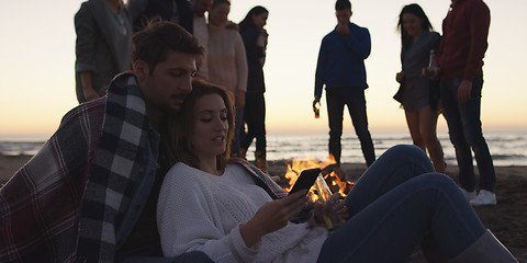 Image showing Couple enjoying bonfire with friends on beach