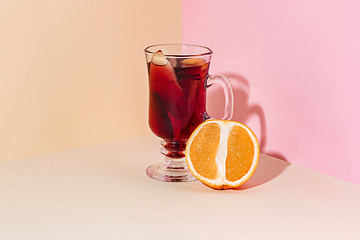 Image showing Mulled wine in glass with cinnamon stick, christmas sweets on on the glass table