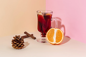 Image showing Mulled wine in glass with cinnamon stick, christmas sweets on on the glass table