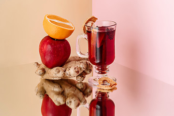 Image showing Mulled wine in glass with cinnamon stick, christmas sweets on on the glass table