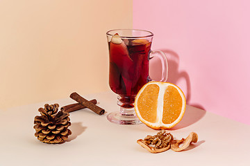 Image showing Mulled wine in glass with cinnamon stick, christmas sweets on on the glass table