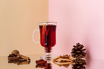 Image showing Mulled wine in glass with cinnamon stick, christmas sweets on on the glass table