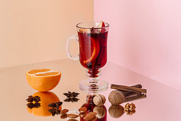 Image showing Mulled wine in glass with cinnamon stick, christmas sweets on on the glass table