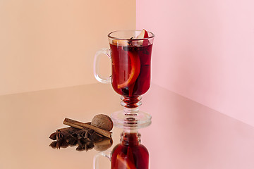 Image showing Mulled wine in glass with cinnamon stick, christmas sweets on on the glass table