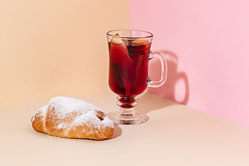 Image showing Mulled wine in glass with cinnamon stick, christmas cake on on the glass table