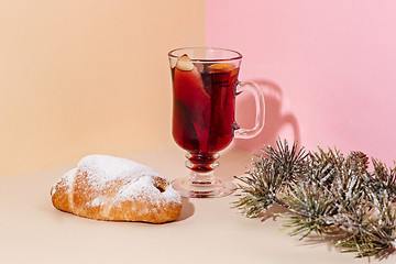 Image showing Mulled wine in glass with cinnamon stick, christmas cake on on the glass table