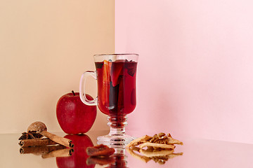Image showing Mulled wine in glass with cinnamon stick, christmas sweets on on the glass table