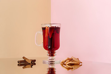 Image showing Mulled wine in glass with cinnamon stick, christmas sweets on on the glass table