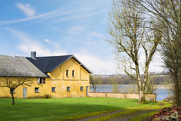 Image showing Yellow farm house by a lake in the spring