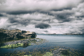 Image showing Cliffs with green seaweed under a dark sky