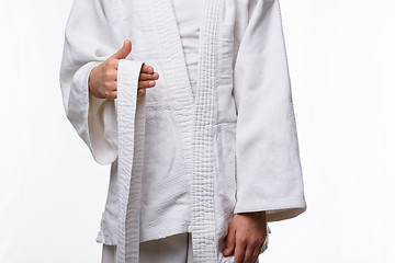 Image showing Stages of correct tying of the belt by a teenager on a sports kimono, step one