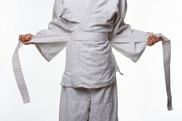 Image showing Stages of correct tying of the belt by a teenager on a sports kimono, step four