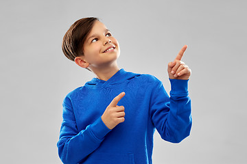 Image showing happy boy in blue hoodie pointing fingers upwards