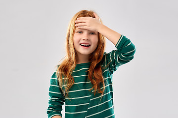 Image showing smiling red haired girl holding to her head