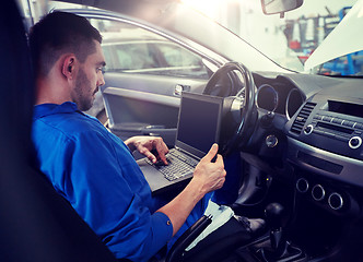 Image showing mechanic man with laptop making car diagnostic